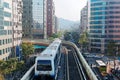 View of a train traveling on elevated tracks of Taipei Metro System between office towers under blue clear sky