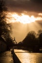 tree silhouettes and suspended bridge silhouette under the river and beautiful cloudy sky by sunset Royalty Free Stock Photo