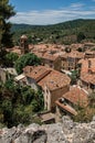 View of trees, house roofs and belfry under sunny blue sky in Moustiers-Sainte-Marie. Royalty Free Stock Photo