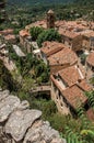 View of trees, house roofs and belfry under sunny blue sky in Moustiers-Sainte-Marie. Royalty Free Stock Photo