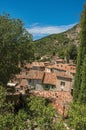 View of trees and house roofs under sunny blue sky in Moustiers-Sainte-Marie. Royalty Free Stock Photo