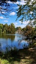 View through the trees of Riverside park bridge Guelph Ontario blue sky clouds blue reflection on water Royalty Free Stock Photo