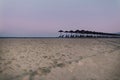 View of tropical beach with big straw umbrellas on the sunset sea background Royalty Free Stock Photo