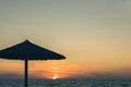 View of tropical beach with big straw umbrellas and sun loungers on the sunset sea background Royalty Free Stock Photo