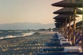 View of tropical beach with big straw umbrellas and sun loungers on the sunset sea background Royalty Free Stock Photo