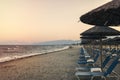 View of tropical beach with big straw umbrellas and sun loungers on the sunset sea background Royalty Free Stock Photo