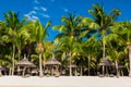 View of tropical beach with chairs and umbrellas, palms and blue sky Royalty Free Stock Photo