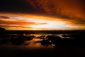 View from tropical beach over stones on dramatic orange yellow sunset over andaman sea with storm clouds, ko lanta Royalty Free Stock Photo