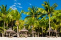 View of tropical resort. Chairs and umbrella with white sand, coconut palms and sky Royalty Free Stock Photo