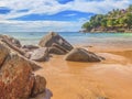 View of a tropical sandy beach with rocks and surging water