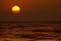 View on tropical sunset with big round sun over ocean horizon, dark shimmering water - Sri Lanka