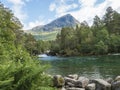 View on turquoise mountain river Slettvikelva cascade with forest and mountains, originating from a thawing glacier