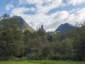 View on turquoise mountain river Slettvikelva with forest and mountains, Norway. Blue sky white clouds. Summer travel