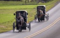 View of Two Amish Horse and Buggies Traveling Down a Countryside Road Thru Farmlands Royalty Free Stock Photo