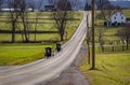 View of Two Amish Horse and Buggies Traveling Down a Countryside Road Thru Farmlands Royalty Free Stock Photo