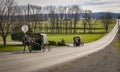 View of Two Amish Horse and Buggies Traveling Down a Countryside Road Thru Farmlands