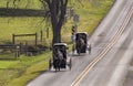 View of Two Amish Horse and Buggies Traveling Down a Countryside Road Thru Farmlands Royalty Free Stock Photo