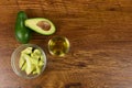 View of two avocados, olive oil bottle and cut avocado in a bowl on wood table background Royalty Free Stock Photo