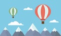 View of two colorful hot air balloons jetting over mountain tops among clouds on blue sky Royalty Free Stock Photo