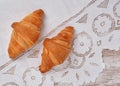 View on two fresh croissants on white vintage richelieu embroidery doily