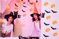 View of two halloween girls through hole in white wall. Festive halloween design. Best friends girls celebrates