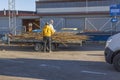 View of two men unloading trailer with old boards into special container at waste recycling station.