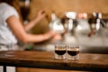 view of two transparent glasses of freshly brewed espresso on wooden table