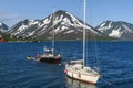 View of two yachts under the white and black sails compete in team sailing event. North Sea, blue sky and mountains as Royalty Free Stock Photo