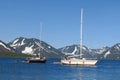 View of two yachts under the white and black sails compete in team sailing event. North Sea, blue sky and mountains as Royalty Free Stock Photo