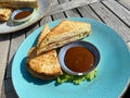 View on typical dutch toasted ham and cheese sandwich on blue plate, bowlwith  red sauce on wood table - Netherlands Royalty Free Stock Photo