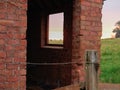 View of a typical English rural landscape through window opening in remains of old brick farm building at sunrise