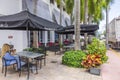 View at typical street-side restaurant scene on one of Miami\'s streets. A lone visitor sits with her mobile phone. .