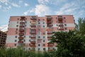 View from underneath on colorful pink apartment building in front of blue sky with clouds. City dwelling. Urban architecture Royalty Free Stock Photo