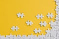 View of unfinished jigsaw near connected white puzzle pieces isolated on yellow