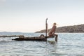 View of unrecognizable woman wearing big summer sun hat tanning topless and relaxing on old wooden pier in remote calm