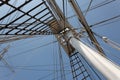 View up the mast of a tall sailing ship with shrouds, ropes, block and tackle, against a blue sky Royalty Free Stock Photo