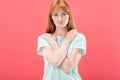 View of upset redhead girl in t-shirt looking at camera isolated on pink