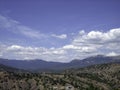 View of a valley of mountains and hills covered with a forest of low trees. Lush clouds float across the blue sky Royalty Free Stock Photo