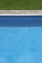 View of various materials by a pool. Blue and dark blue water, a concrete edge, paving slabs, green lawn. Different Royalty Free Stock Photo