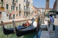 View of Venetian canal with gondolas, tourists are visiting the neighborhood