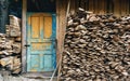 View at a village storage house for tools and fire woods. Vintage painted door in blue color. Paint is partially pilled off.