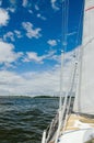 View of the water and the distant shore from the side of a sailboat with rigging and sails Royalty Free Stock Photo