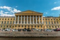 View from the water to a beautiful yellow building with columns on the embankment of St. Petersburg, Russia