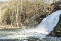 View of a waterfall with a rainbow reflected in the water with an arid vegetation in the background in the small city of Spa Belgi Royalty Free Stock Photo