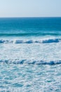 View of waves with foam, over blue sea and clear sky, a summer afternoon in Cantabria Royalty Free Stock Photo