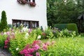 View of the well-kept garden with a green lawn, flowers and trees near the house