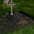 View of a well-kept grave in a large cemetery with a massive cross in the summer