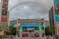 View on the Wembley stadium with two red double decker buses in front and dark stormy sky in the background