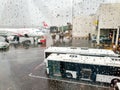 View through wet window and water droplets on airpalne and airport terminal during rain