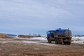 View from a wheel of the off-road truck riding in a dirt road on cloudy sky background. Scene. Close up for red cab of a lorry Royalty Free Stock Photo